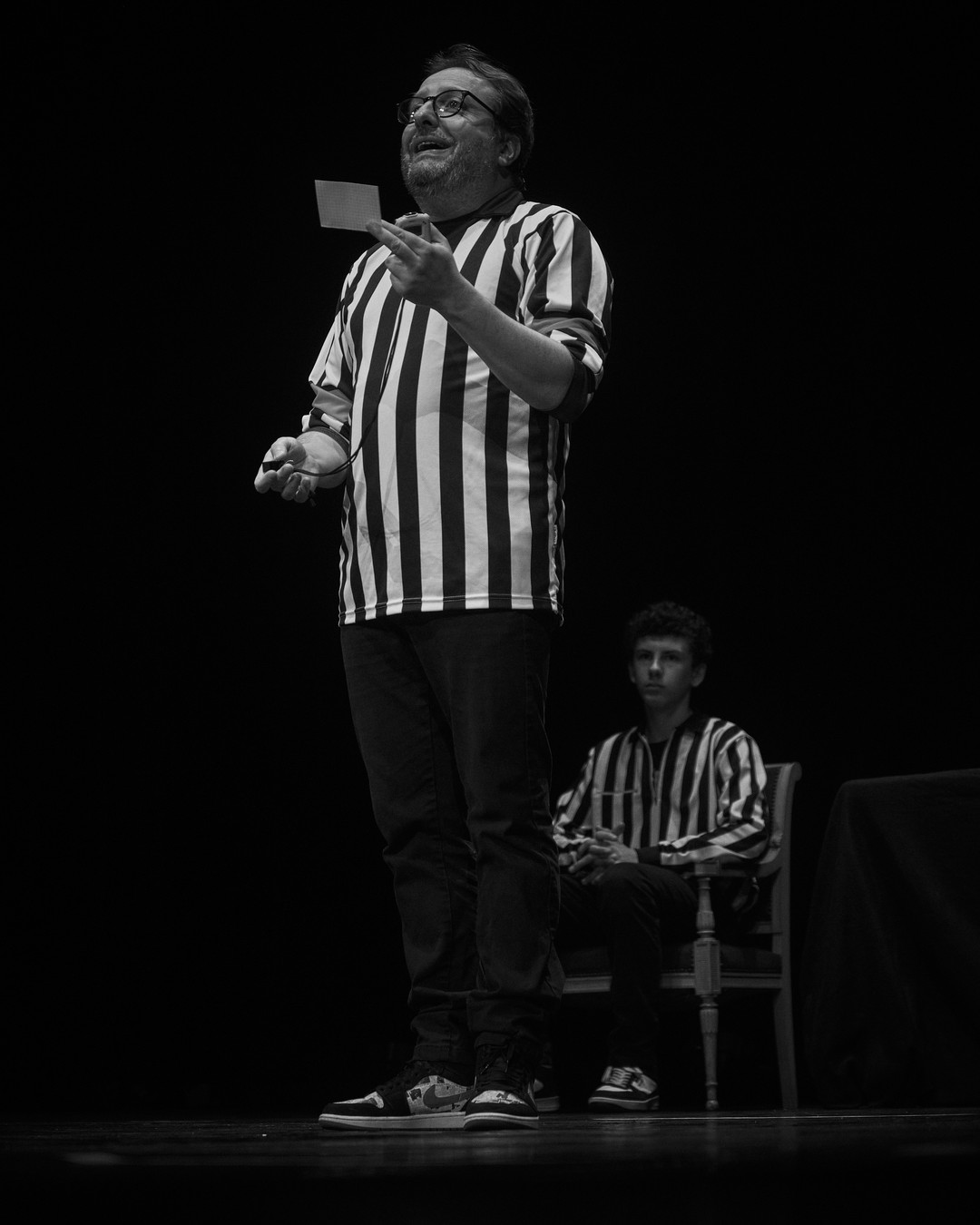 Un árbitro del partido de improvisación presenta una tarjeta en el escenario.