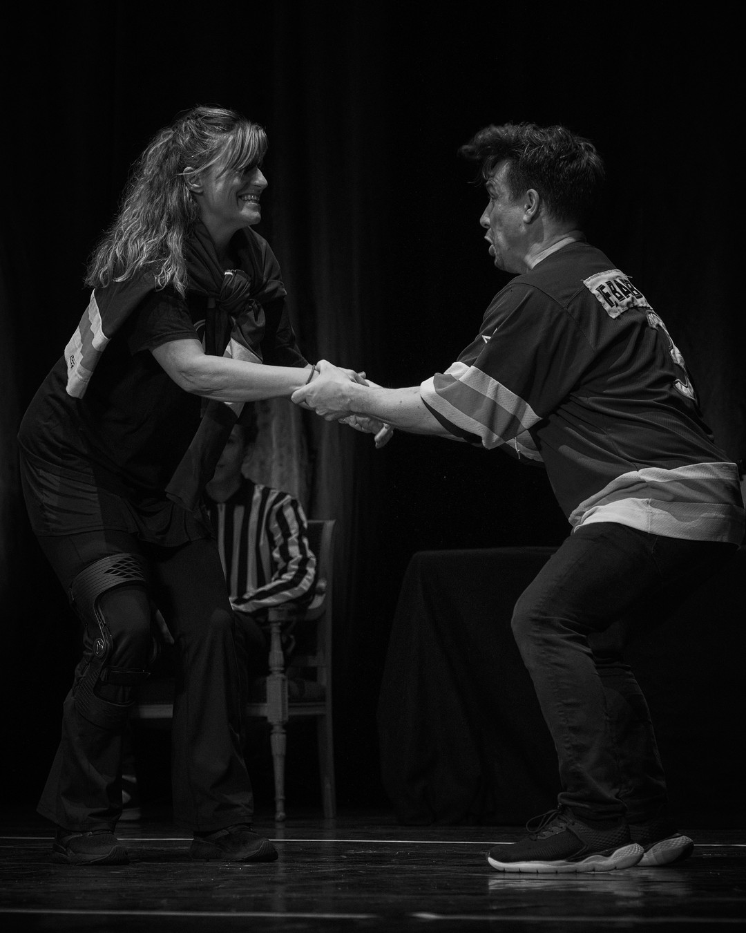 Dos actores se miran y se dan la mano en el escenario.