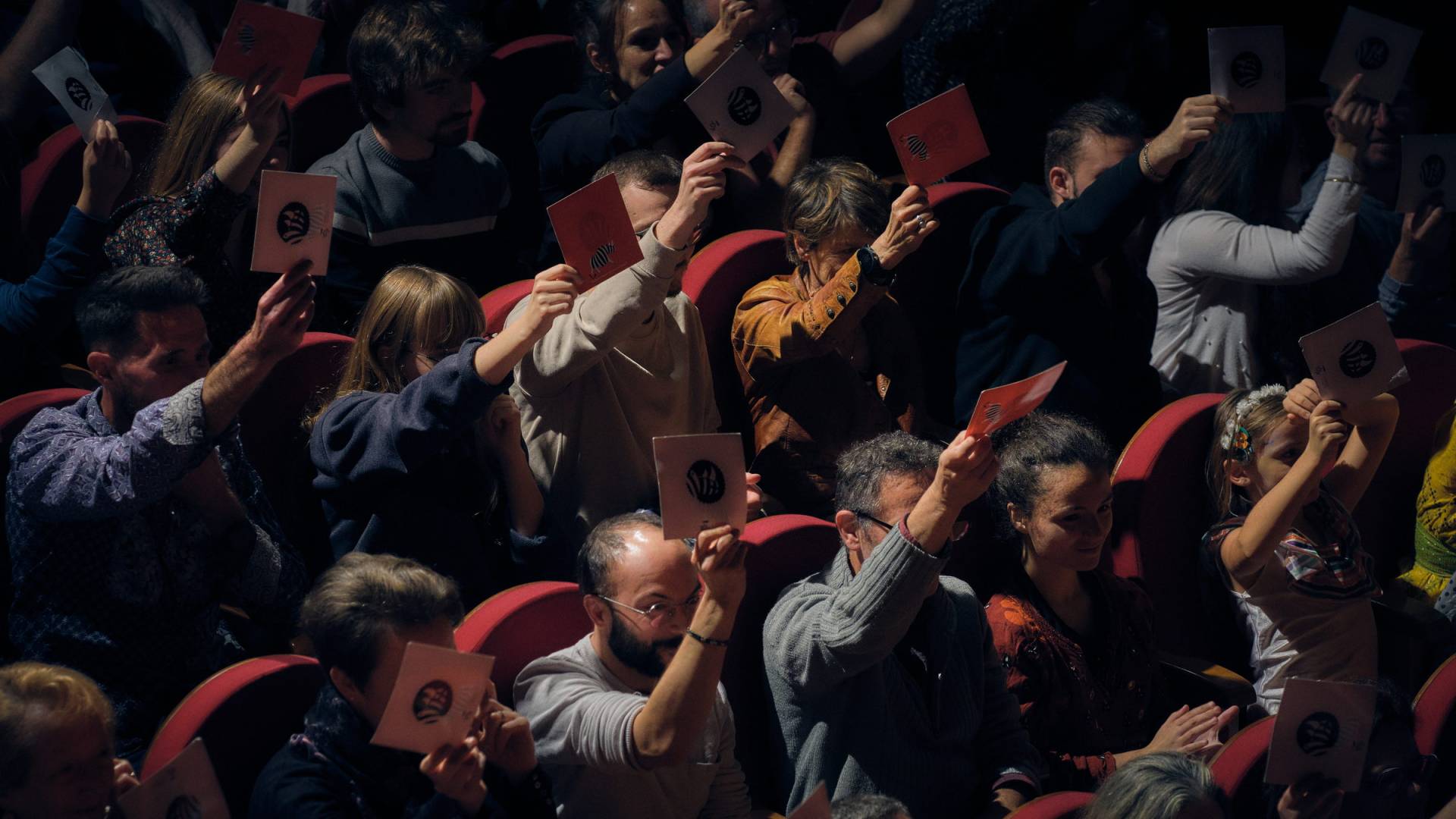 Le public du théâtre lève ses cartons pour voter.