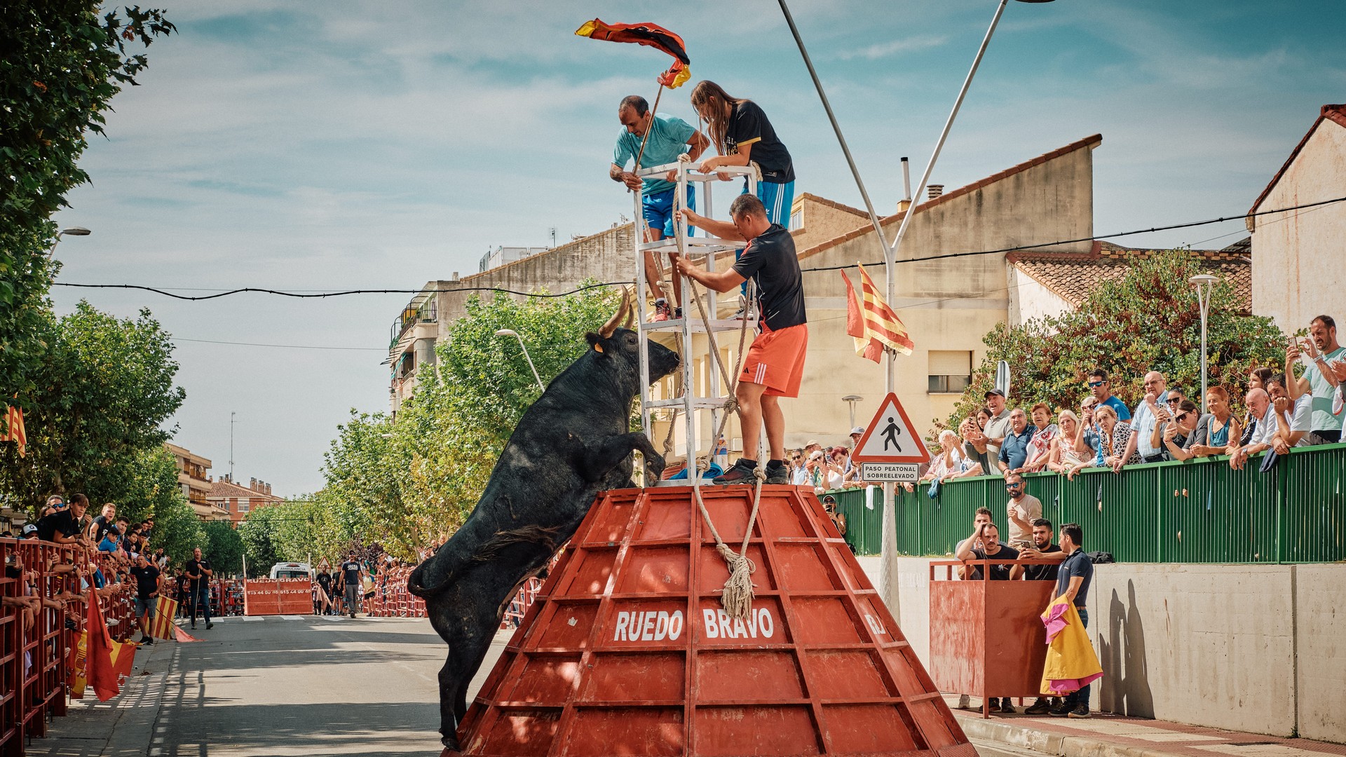Un toro se encabrita frente a una estructura roja rodeada de público.